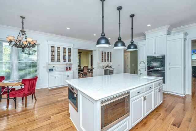 entryway featuring light wood-type flooring, a healthy amount of sunlight, a chandelier, and ornamental molding