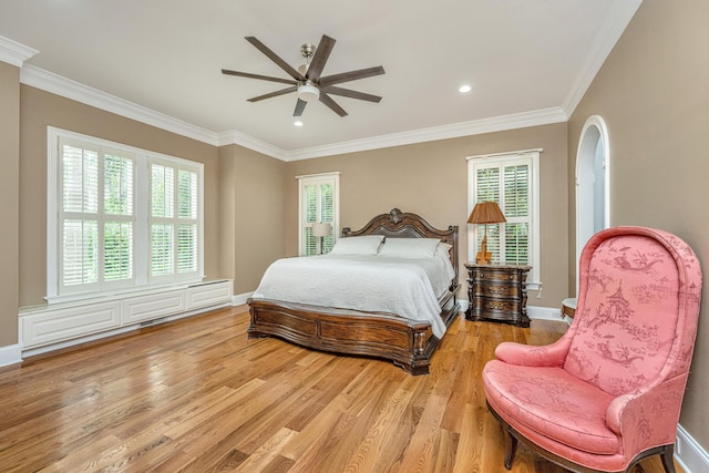 bedroom with baseboards, crown molding, and light wood finished floors