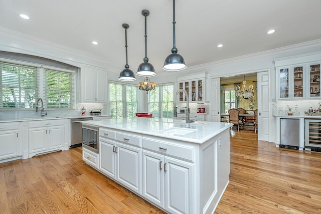 kitchen featuring white cabinets, a kitchen island with sink, and light countertops