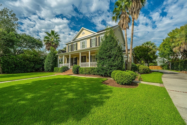 colonial inspired home featuring covered porch and a front lawn