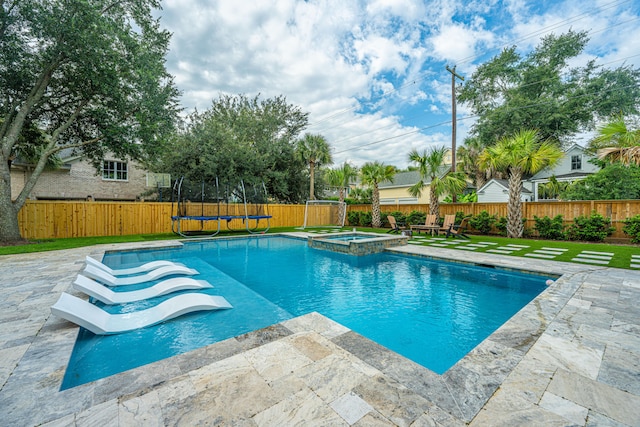 view of swimming pool featuring an in ground hot tub, a trampoline, a patio, and a lawn