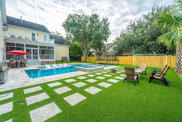 view of pool with a trampoline, a sunroom, a fenced backyard, and a yard