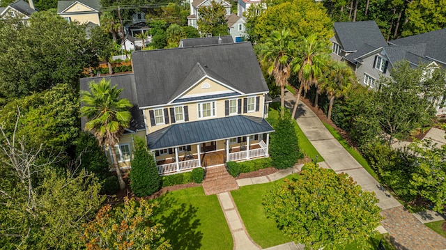 view of front of home featuring covered porch, metal roof, a front lawn, and a standing seam roof