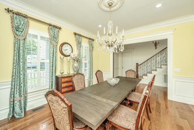 dining area with light wood finished floors, an inviting chandelier, visible vents, and crown molding