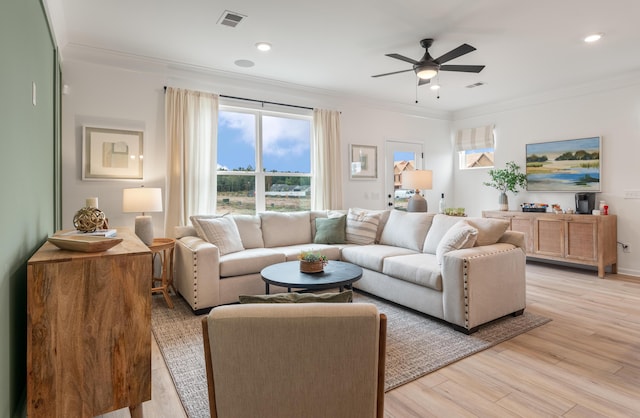 living area featuring a wealth of natural light, ornamental molding, and visible vents