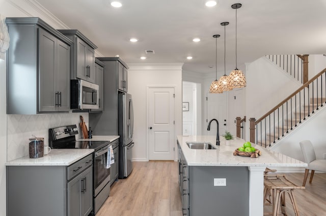 kitchen with stainless steel appliances, a sink, a kitchen breakfast bar, gray cabinets, and crown molding