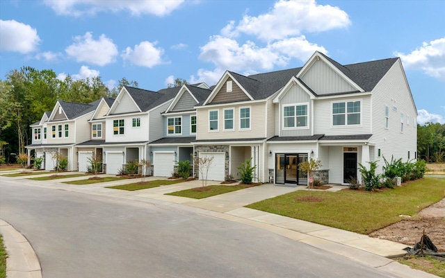 multi unit property featuring a garage, driveway, a residential view, a front lawn, and board and batten siding