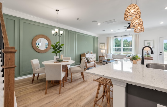 kitchen featuring green cabinets, ornamental molding, a sink, and a decorative wall