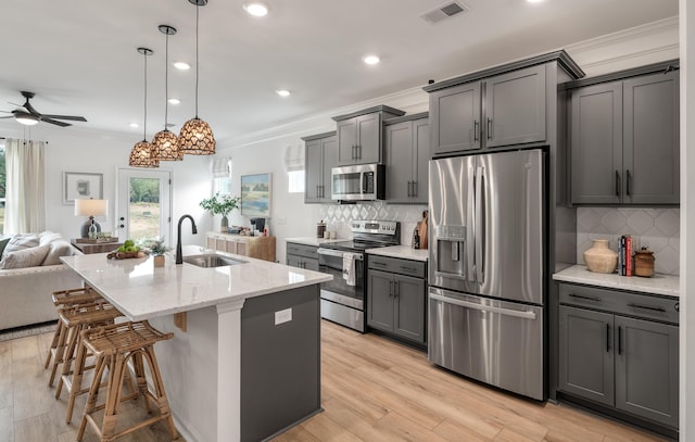 kitchen featuring visible vents, appliances with stainless steel finishes, open floor plan, a sink, and light stone countertops