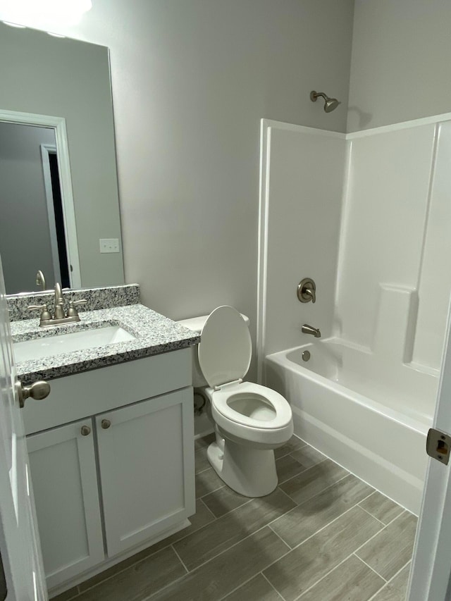 bathroom featuring toilet, wood tiled floor, vanity, and shower / bathtub combination