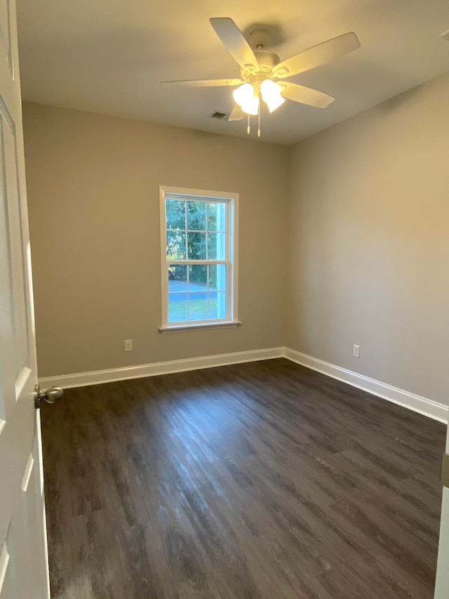 spare room featuring dark wood-style floors, ceiling fan, visible vents, and baseboards