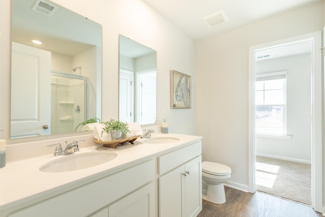 bathroom with toilet, vanity, a shower with shower door, and wood-type flooring