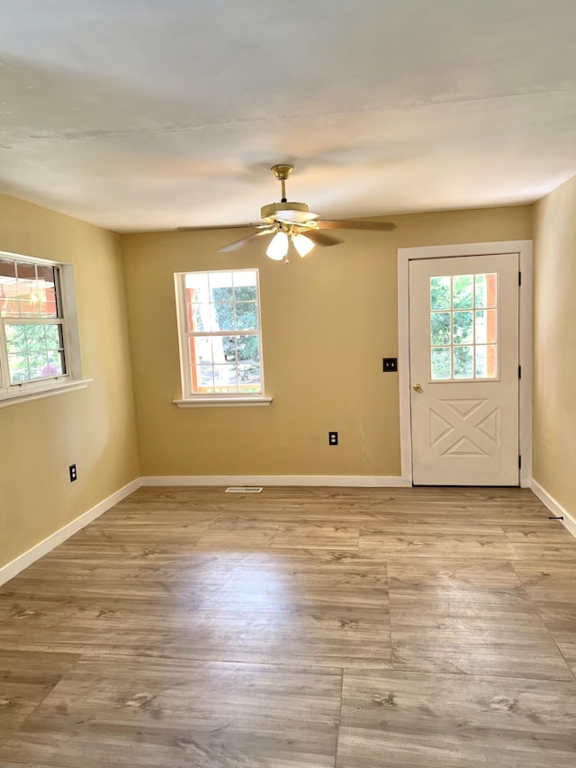 interior space featuring baseboards, ceiling fan, wood finished floors, and visible vents