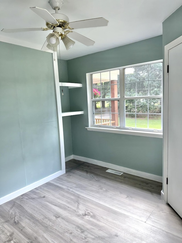 unfurnished room with baseboards, ceiling fan, wood finished floors, and visible vents