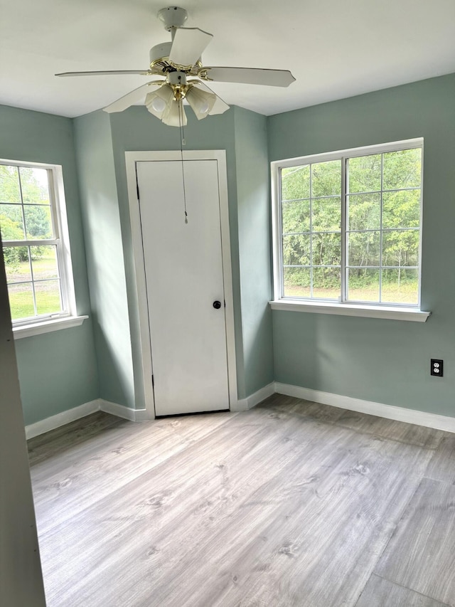 unfurnished bedroom featuring baseboards, multiple windows, and wood finished floors