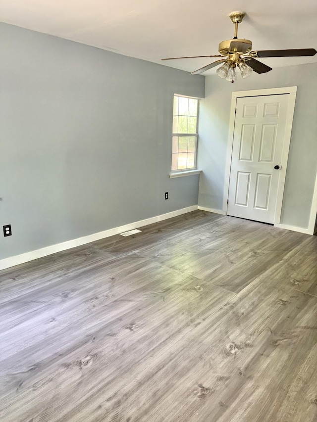 unfurnished bedroom with baseboards, ceiling fan, wood finished floors, and visible vents