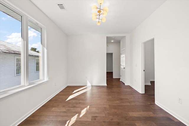 empty room featuring dark hardwood / wood-style floors and a notable chandelier