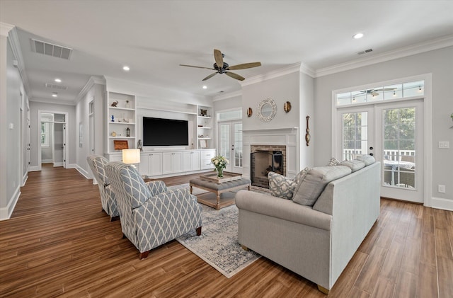 living room featuring french doors, a stone fireplace, crown molding, hardwood / wood-style flooring, and ceiling fan