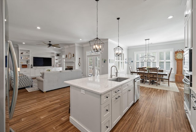 kitchen featuring white cabinets, hanging light fixtures, a kitchen island with sink, and sink