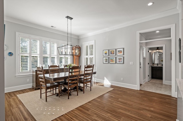 dining area with dark hardwood / wood-style floors, an inviting chandelier, and crown molding