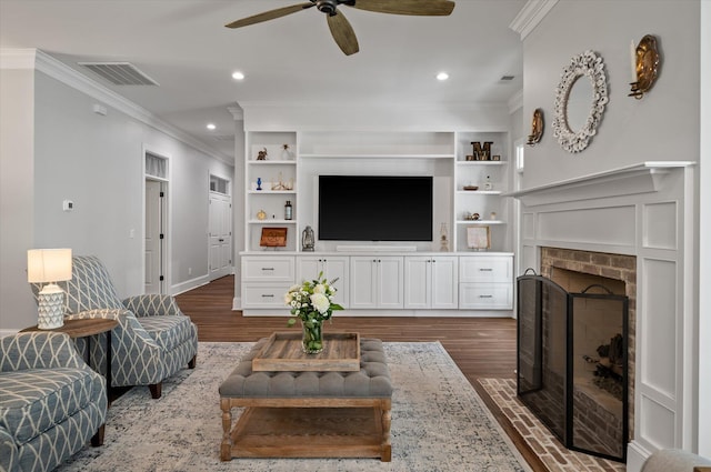 living room with built in shelves, ceiling fan, crown molding, and a fireplace