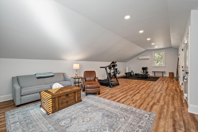 living area featuring a wall mounted air conditioner, wood-type flooring, and lofted ceiling