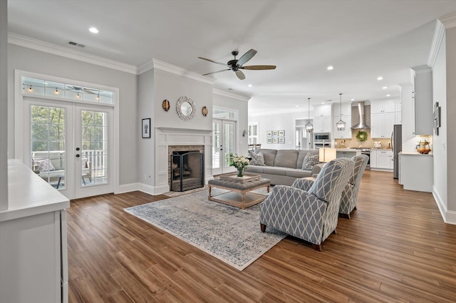 living room with french doors, a brick fireplace, ornamental molding, ceiling fan, and dark hardwood / wood-style floors