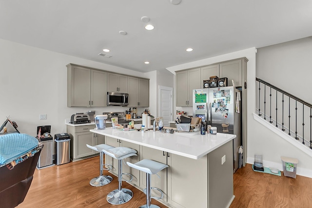 7812 Park Gate Dr, North Charleston, SC 29418 - kitchen with gray cabinetry, stainless steel appliances, light wood-type flooring, recessed lighting, and an island with sink