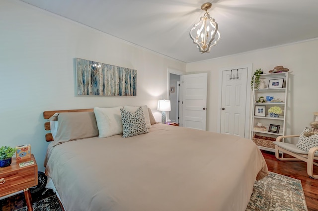 bedroom featuring dark wood-style flooring, a chandelier, and crown molding