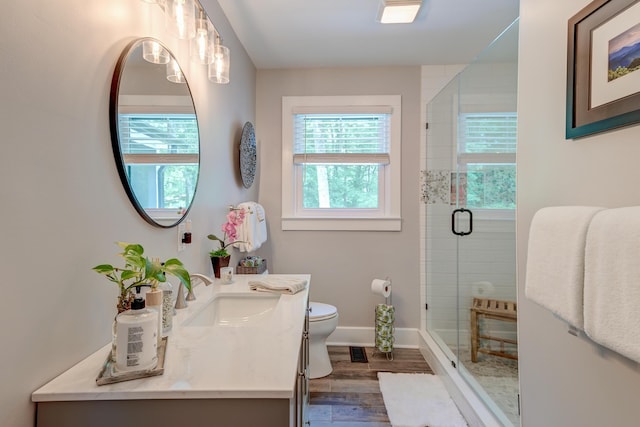 full bathroom featuring wood finished floors, toilet, a shower stall, baseboards, and vanity