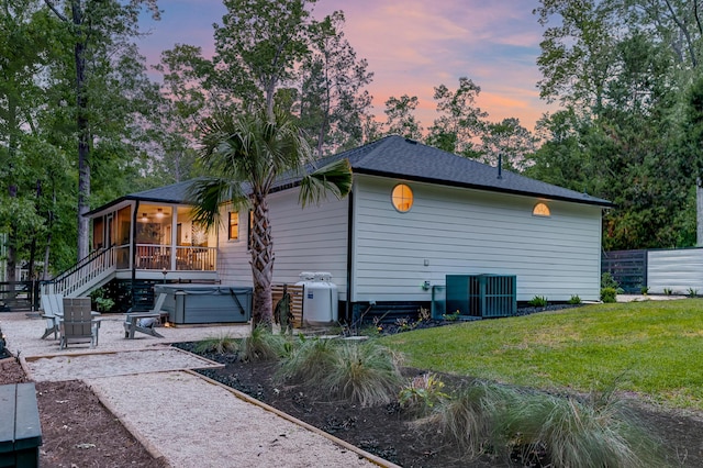 view of side of home with a hot tub, a sunroom, a patio, and cooling unit