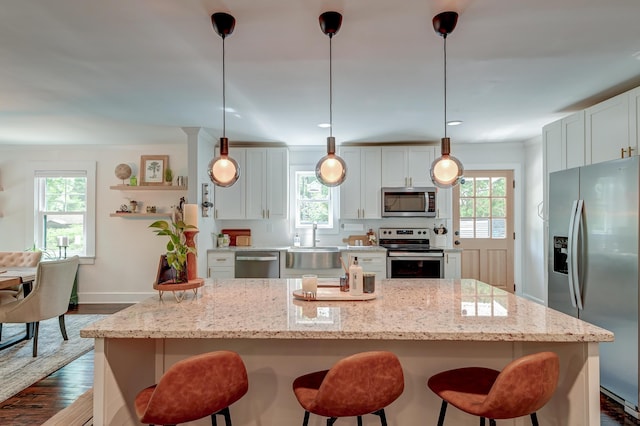 kitchen with appliances with stainless steel finishes, a breakfast bar, dark wood-style flooring, and a sink