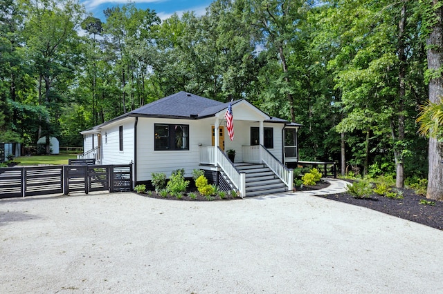 bungalow-style home with a gate, a porch, stairway, and view of scattered trees