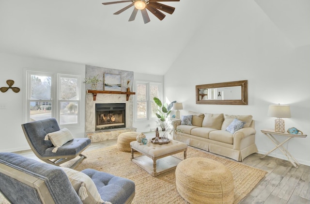 living room featuring a large fireplace, ceiling fan, plenty of natural light, and light wood-type flooring