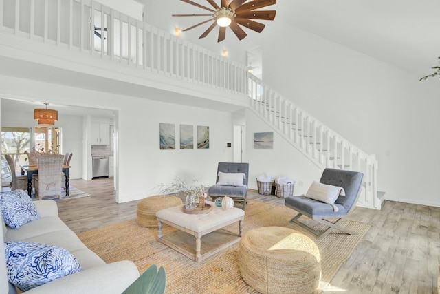 living room with light hardwood / wood-style flooring, high vaulted ceiling, and ceiling fan