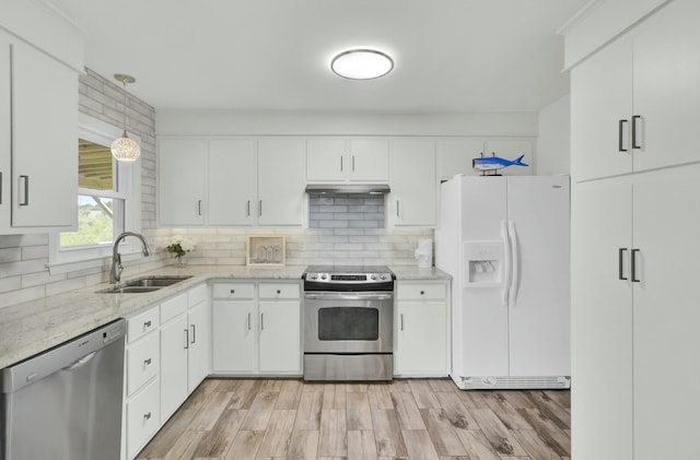 kitchen featuring stainless steel appliances, sink, white cabinets, light hardwood / wood-style floors, and hanging light fixtures