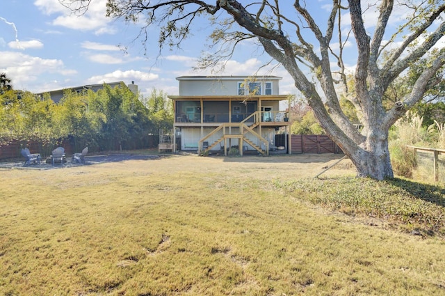 rear view of house featuring a sunroom and a lawn