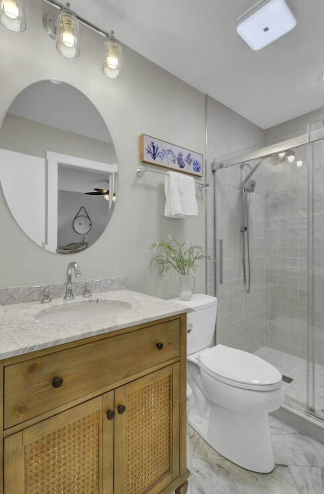 bathroom with vanity, toilet, ceiling fan, and a shower with shower door