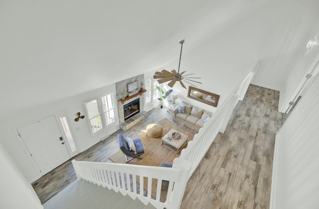 living room with high vaulted ceiling, light hardwood / wood-style flooring, ceiling fan, and a stone fireplace