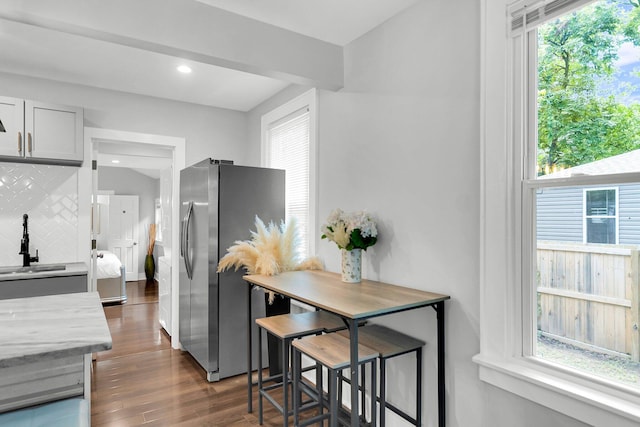 kitchen featuring dark hardwood / wood-style floors, stainless steel fridge, a wealth of natural light, and backsplash