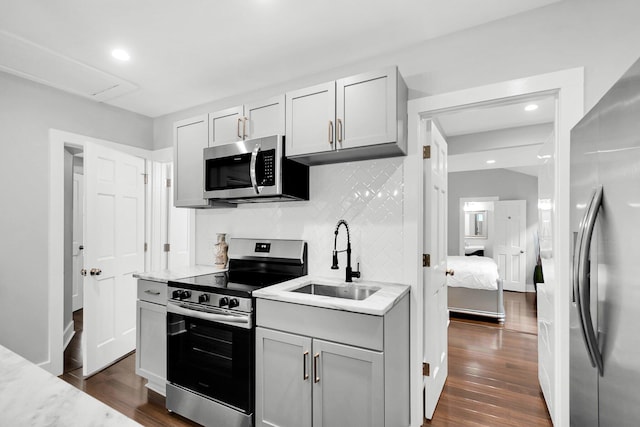 kitchen with sink, light stone counters, dark hardwood / wood-style floors, stainless steel appliances, and backsplash