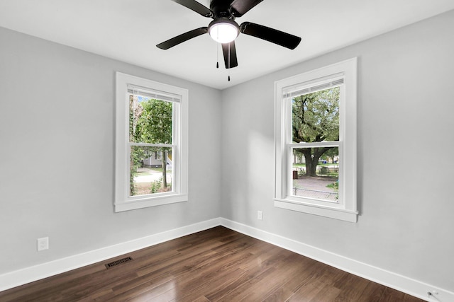 spare room featuring dark hardwood / wood-style flooring, ceiling fan, and plenty of natural light