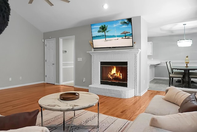 living room featuring a fireplace, ceiling fan, and light wood-type flooring