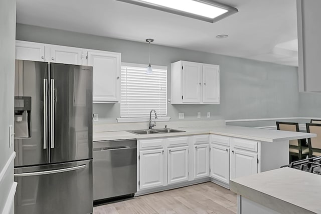 kitchen with pendant lighting, sink, stainless steel appliances, and white cabinets