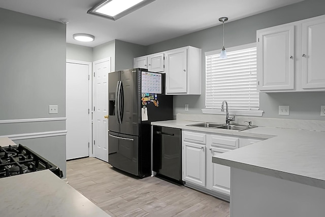 kitchen with sink, light hardwood / wood-style flooring, white cabinetry, hanging light fixtures, and black appliances