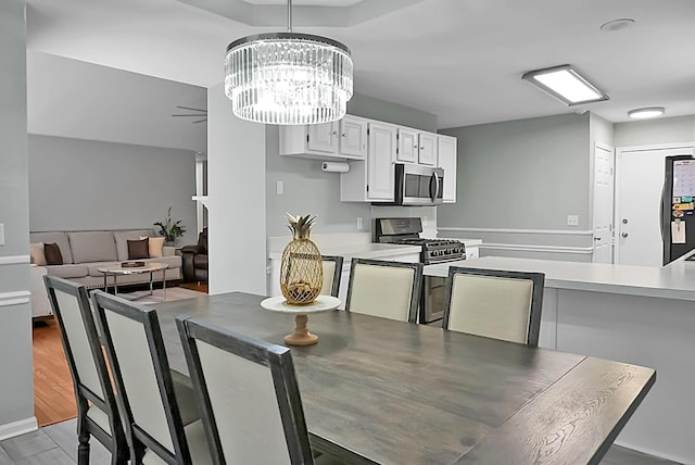 dining room featuring dark hardwood / wood-style flooring and ceiling fan with notable chandelier