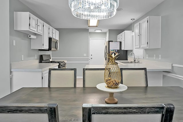 kitchen with stainless steel appliances, white cabinetry, sink, and a notable chandelier