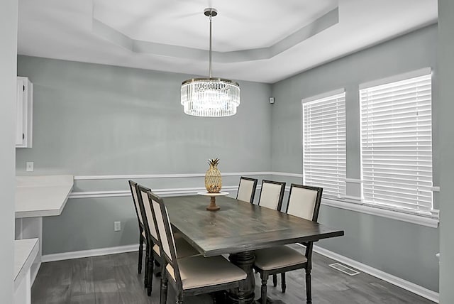 dining room featuring dark hardwood / wood-style floors, a tray ceiling, and a chandelier