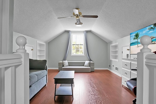 living room with built in shelves, vaulted ceiling, and a textured ceiling