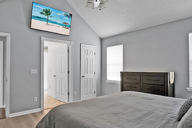 bedroom featuring lofted ceiling, a textured ceiling, and light hardwood / wood-style floors